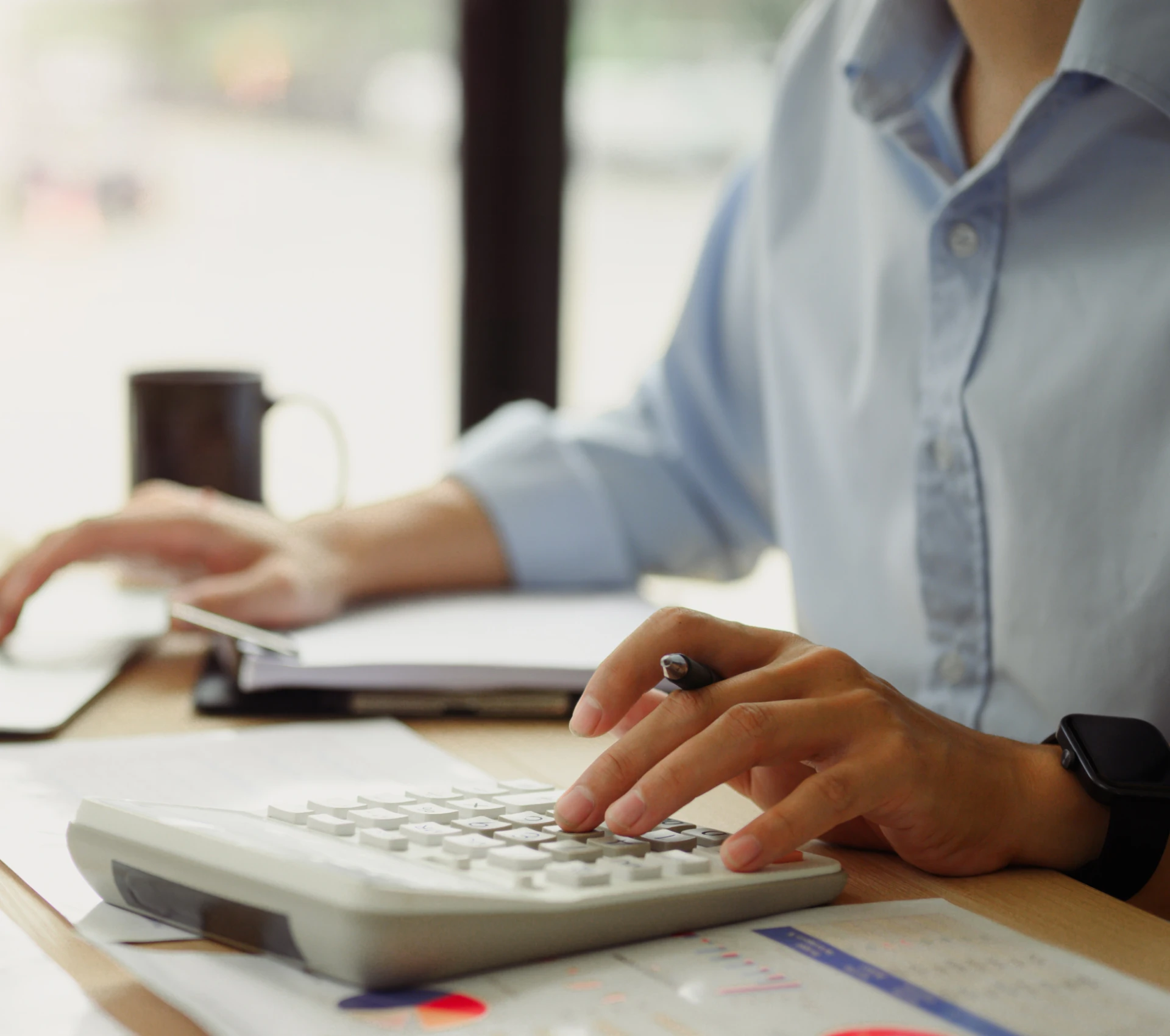 Hands typing on calculator in office